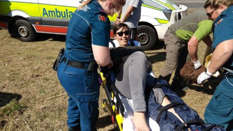 Amellia Formby on a stretcher with a broken leg being attended by two paramedics